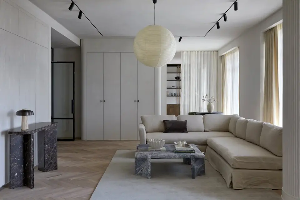 Living room at The Whiteley, Bayswater, with a paper globe pendant, plaster walls and a curved sofa